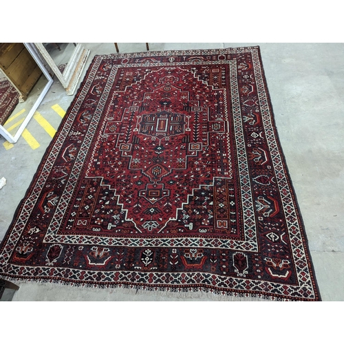 1057 - A Caucasian design burgundy ground carpet, 280 x 210cm