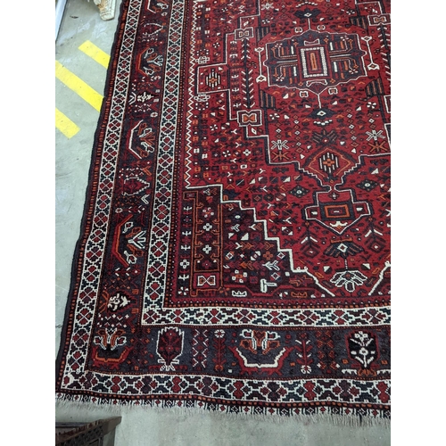 1057 - A Caucasian design burgundy ground carpet, 280 x 210cm