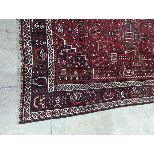 1057 - A Caucasian design burgundy ground carpet, 280 x 210cm