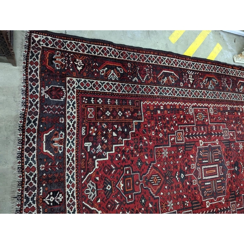 1057 - A Caucasian design burgundy ground carpet, 280 x 210cm