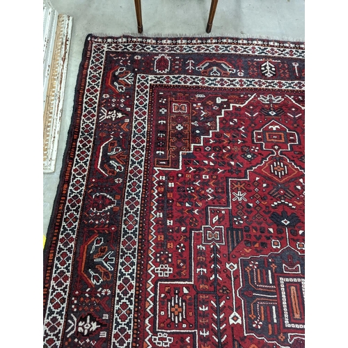 1057 - A Caucasian design burgundy ground carpet, 280 x 210cm