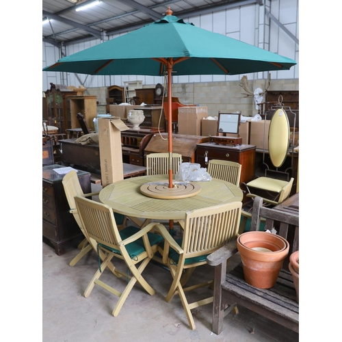 1120 - A teak garden set comprising circular table 148 cms diameter height 75 cms with 'Lazy Susan', paraso... 