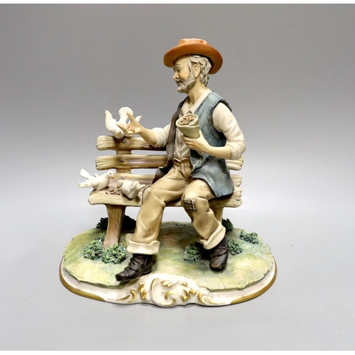 1609 - A Capodimonte figure of a tramp sat on a bench feeding doves 27cm