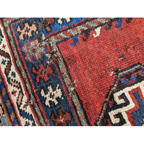 24 - A Caucasian red ground rug, 210 x 110cm