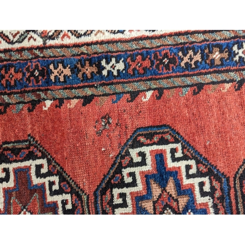 24 - A Caucasian red ground rug, 210 x 110cm