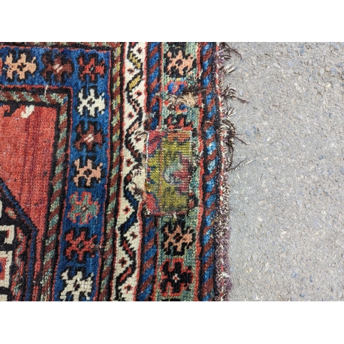 24 - A Caucasian red ground rug, 210 x 110cm