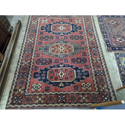 1043 - A Caucasian design red ground carpet, 240 x 176cm