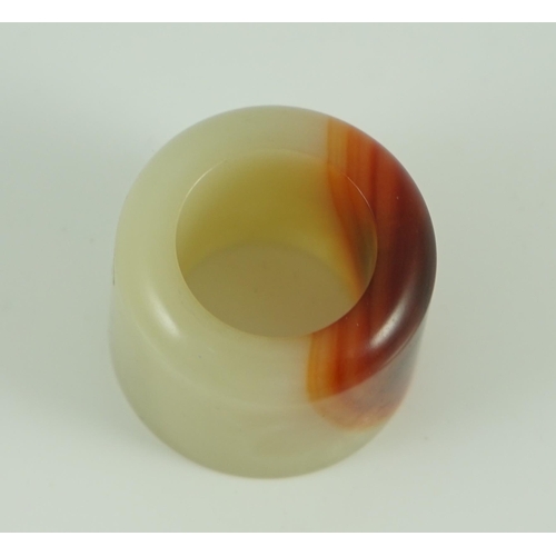 216 - A Chinese pale celadon and russet jade archer's ring, early 20th century 3.4 cm diameter