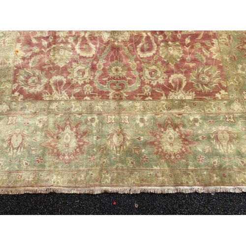 294 - An Indian Agra carpet, with central field of stylised floral motifs on a red ground within a triple ... 