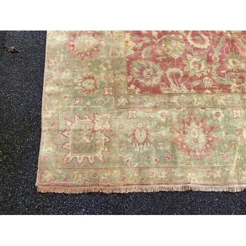 294 - An Indian Agra carpet, with central field of stylised floral motifs on a red ground within a triple ... 