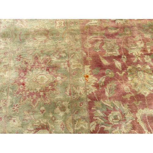 294 - An Indian Agra carpet, with central field of stylised floral motifs on a red ground within a triple ... 