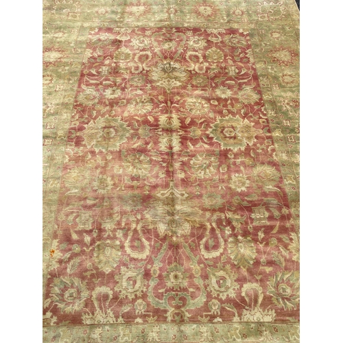 294 - An Indian Agra carpet, with central field of stylised floral motifs on a red ground within a triple ... 