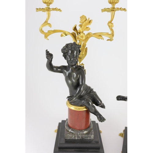 72 - A pair of Louis XVI style bronze and ormolu two light candelabra, each with seated putto stem and sc... 