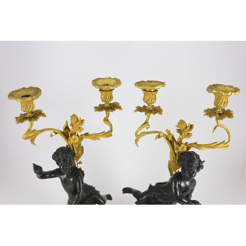 72 - A pair of Louis XVI style bronze and ormolu two light candelabra, each with seated putto stem and sc... 