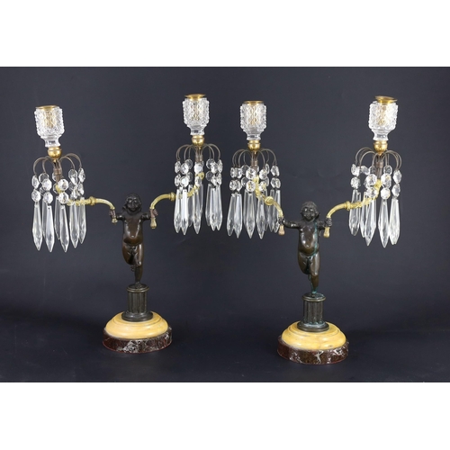 73 - A pair of early 19th century bronze and ormolu figural candelabra, each modelled as a cherub holding... 