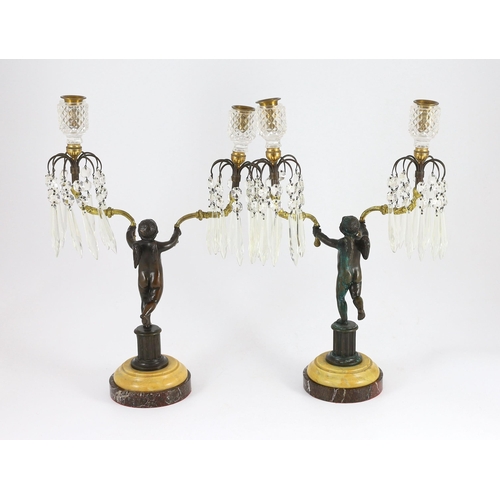 73 - A pair of early 19th century bronze and ormolu figural candelabra, each modelled as a cherub holding... 