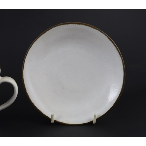 86 - Dame Lucie Rie (1902-1995) a cup, saucer and side plate, c.1959, each white glazed stoneware with ma... 