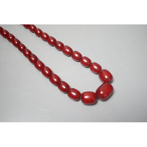 1918 - A single strand graduated oval simulated cherry amber bead necklace, 78cm, gross weight 121 grams.... 