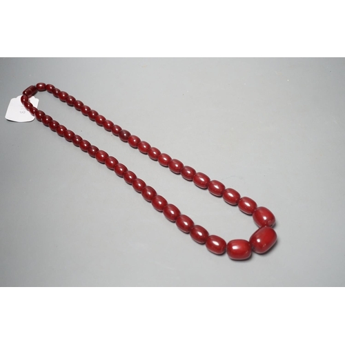 1918 - A single strand graduated oval simulated cherry amber bead necklace, 78cm, gross weight 121 grams.... 