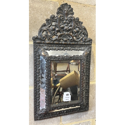 19 - A Dutch brass framed cushion wall mirror, with ornate arched cresting, pierced and repousse with bir... 