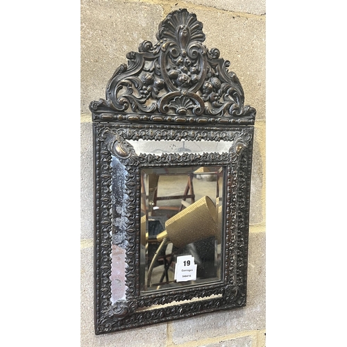 19 - A Dutch brass framed cushion wall mirror, with ornate arched cresting, pierced and repousse with bir... 
