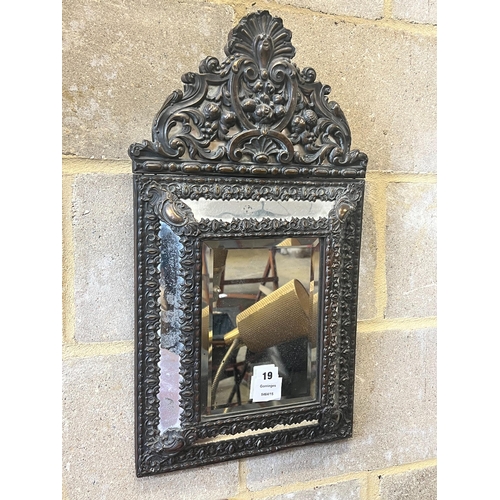 19 - A Dutch brass framed cushion wall mirror, with ornate arched cresting, pierced and repousse with bir... 