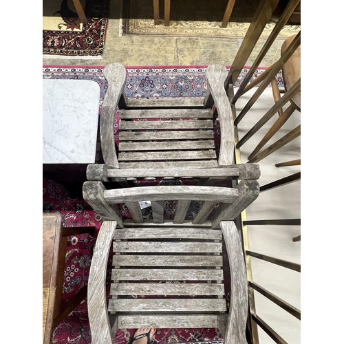 53 - A pair of weathered teak slatted garden elbow chairs, width 64cm depth 60cm height 86cm