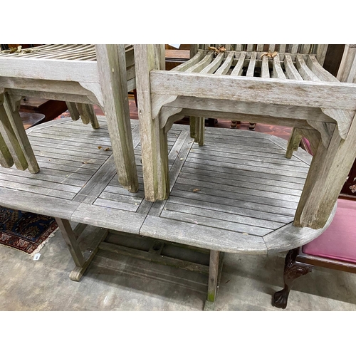 1069 - A weathered teak extending garden table, 180cm extended, width 90cm, height 74cm and six stacking ch... 