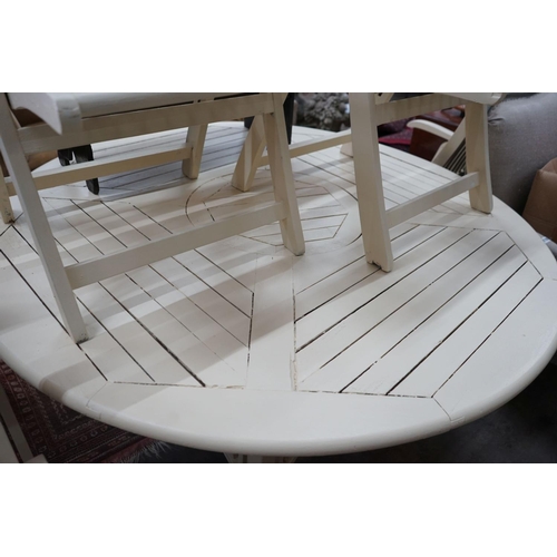 1084 - A circular painted teak garden table, diameter 150cm, height 72cm and six folding elbow chairs... 