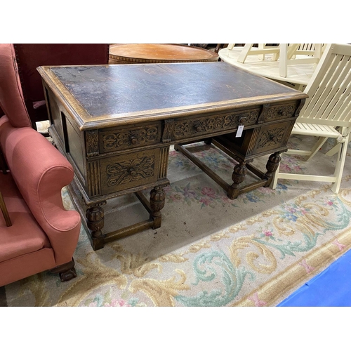 1115 - A 1920's Jacobean revival carved oak five drawer kneehole desk, length 144cm, depth 83cm, height 75c... 