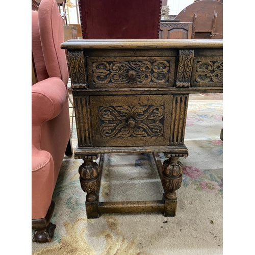 1115 - A 1920's Jacobean revival carved oak five drawer kneehole desk, length 144cm, depth 83cm, height 75c... 