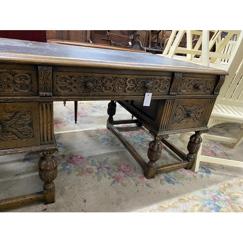 1115 - A 1920's Jacobean revival carved oak five drawer kneehole desk, length 144cm, depth 83cm, height 75c... 