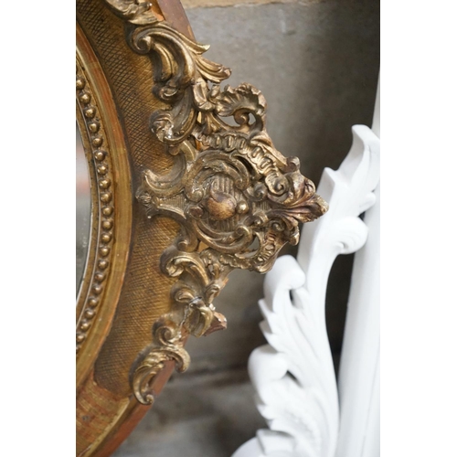 1133 - A 19th century French oval giltwood and gesso wall mirror with pierced 'C' scroll and shell pediment... 