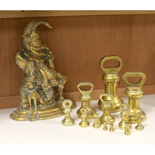 1407 - A graduated set of twelve brass bell weights and a cast brass Punch door stop. 30cm