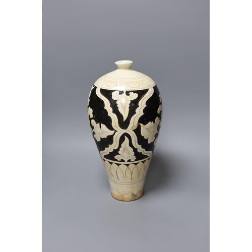 328 - A black and white carved Chinese peony earthenware vase, 34cm tall