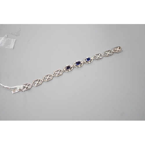 974 - A modern 9ct white metal and three stone emerald cut synthetic sapphire set pierced link bracelet, a... 