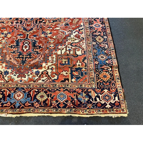 201 - An Heriz red ground carpet, with a lobed central medallion within a floral field and wide conforming... 