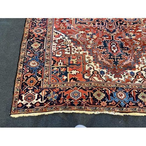 201 - An Heriz red ground carpet, with a lobed central medallion within a floral field and wide conforming... 