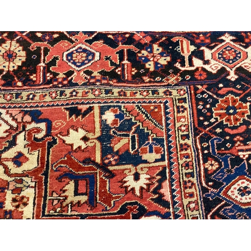 201 - An Heriz red ground carpet, with a lobed central medallion within a floral field and wide conforming... 