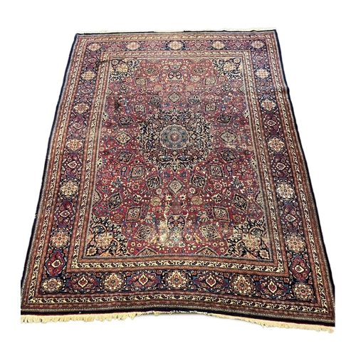 203 - An early 20th century Heriz burgundy ground carpet, woven with a circular floral central medallion w... 