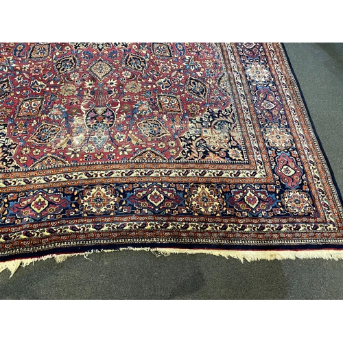 203 - An early 20th century Heriz burgundy ground carpet, woven with a circular floral central medallion w... 