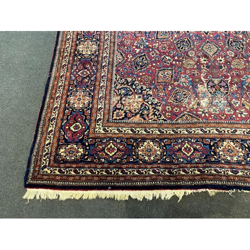 203 - An early 20th century Heriz burgundy ground carpet, woven with a circular floral central medallion w... 