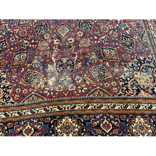 203 - An early 20th century Heriz burgundy ground carpet, woven with a circular floral central medallion w... 