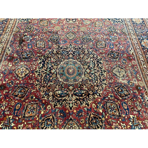 203 - An early 20th century Heriz burgundy ground carpet, woven with a circular floral central medallion w... 