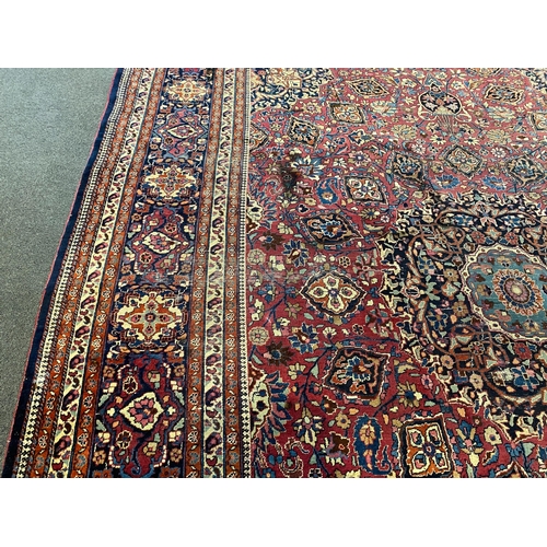 203 - An early 20th century Heriz burgundy ground carpet, woven with a circular floral central medallion w... 