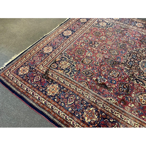 203 - An early 20th century Heriz burgundy ground carpet, woven with a circular floral central medallion w... 