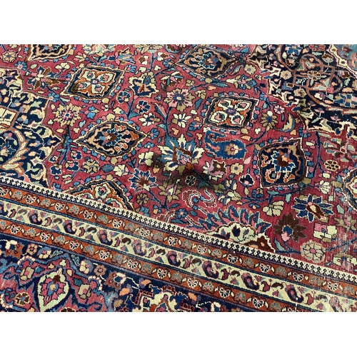 203 - An early 20th century Heriz burgundy ground carpet, woven with a circular floral central medallion w... 