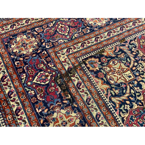 203 - An early 20th century Heriz burgundy ground carpet, woven with a circular floral central medallion w... 