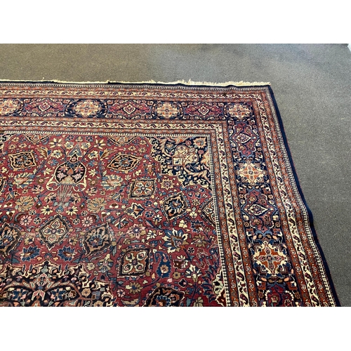 203 - An early 20th century Heriz burgundy ground carpet, woven with a circular floral central medallion w... 