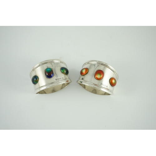 358 - Two similar Edwardian Arts & Crafts silver and enamelled napkin rings, each set with three cabochon ... 